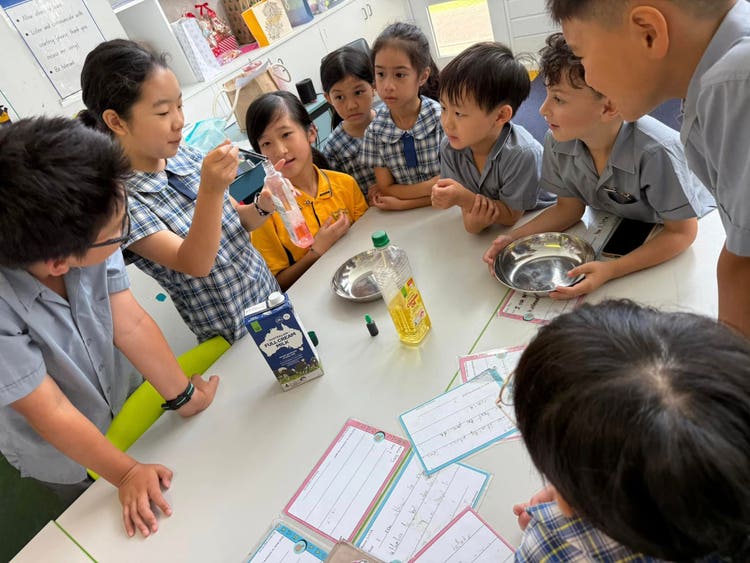 Three older students demonstrating a science experiment with younger students