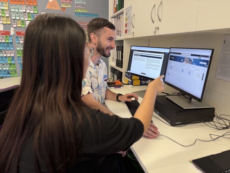 two staff members looking at their computer screen