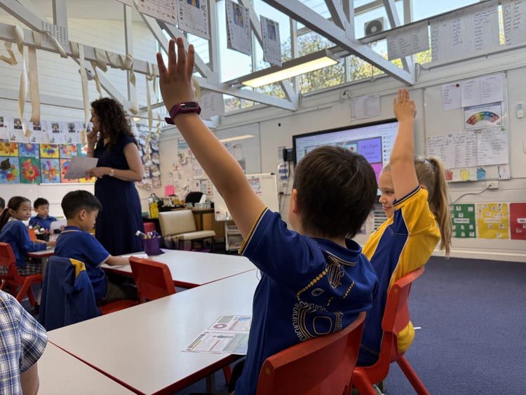 boy and girl with their hand up in classroom