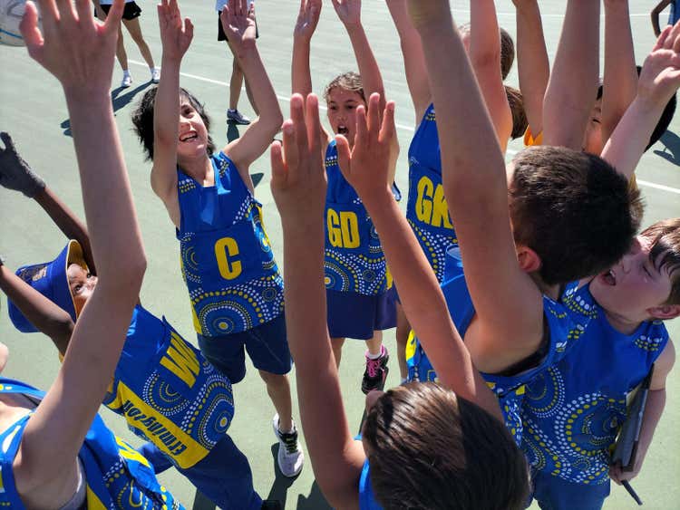 students standing in a circle with their hands up, celebrating
